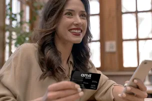 Mulher segurando um cartão Amil e um celular